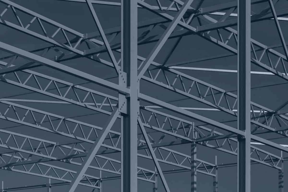 Steel joists and a bolted column-to-beam connection on a commercial building frame against the sky.