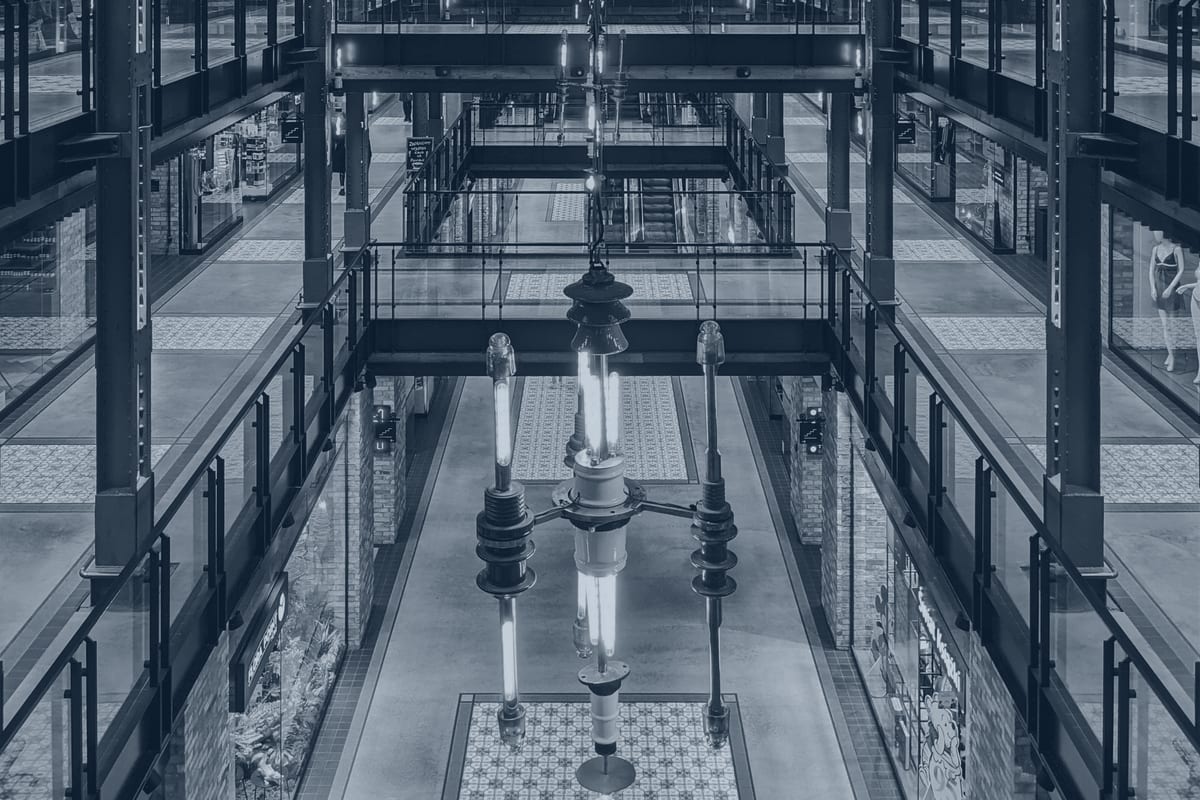 Exposed structural steel columns and beams in a multi-level retail arcade.