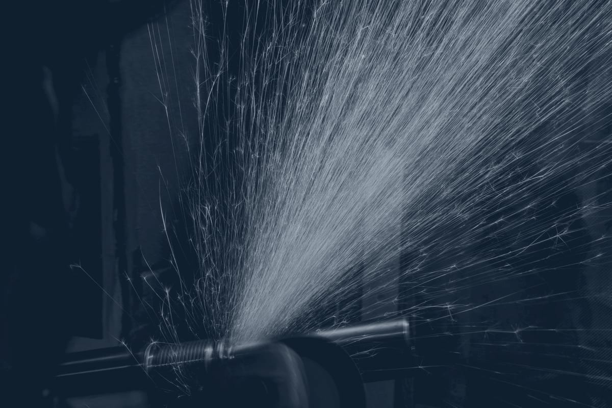 Plasma torch cutting steel plate in a fabrication shop, sparks trailing.