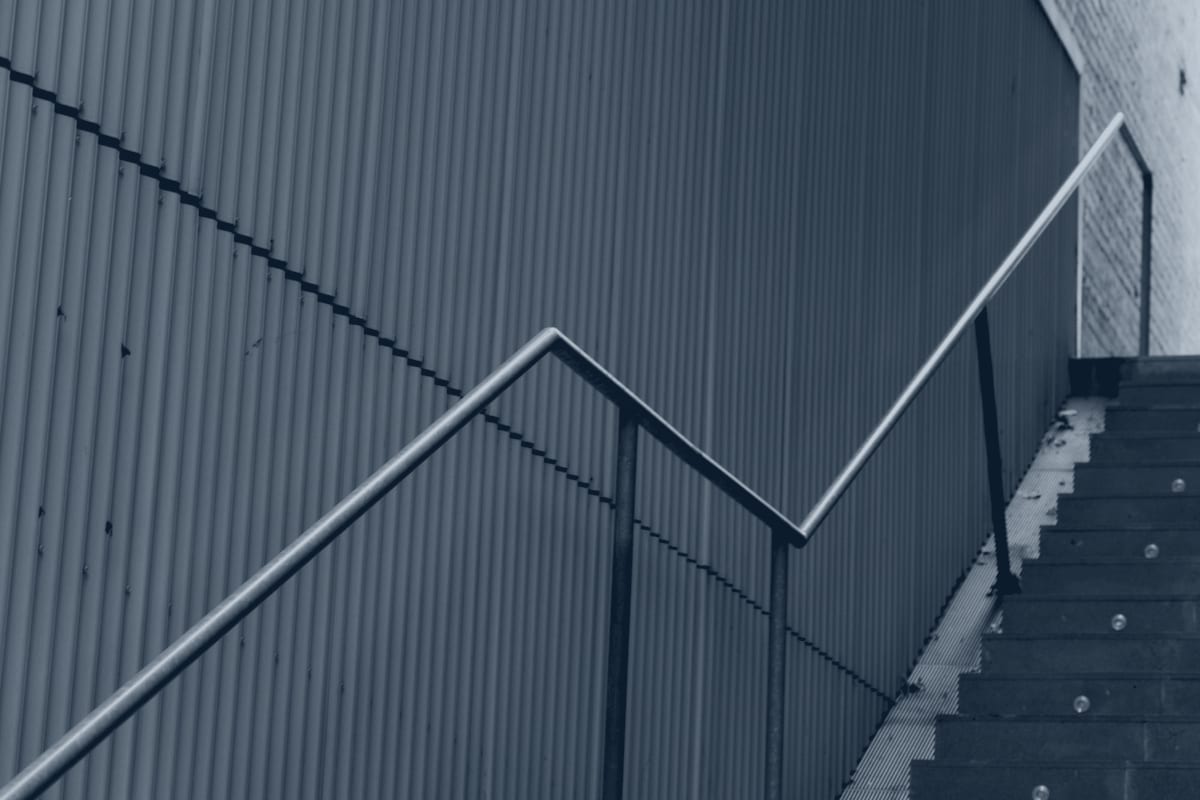 Galvanized steel egress staircase with tubular metal railing.